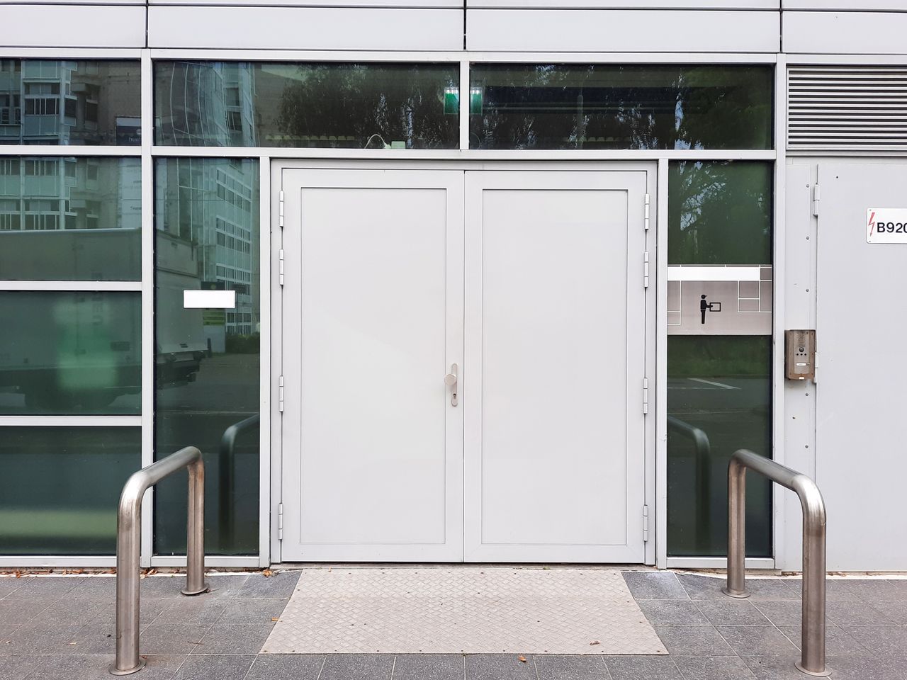 Services Front view of a modern glass building entrance featuring double doors and sleek design elements.